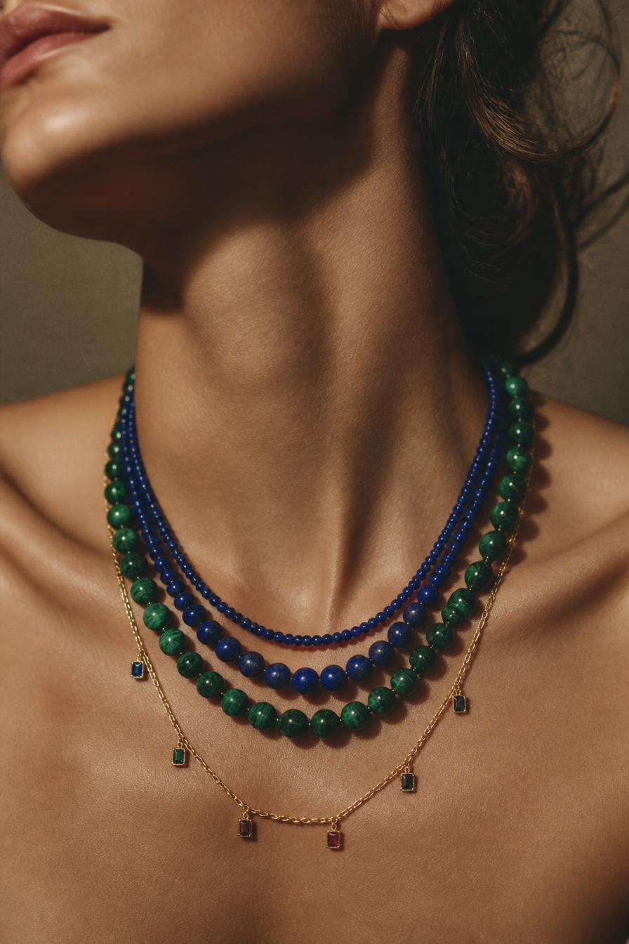 Model wearing stacked lapis, malachite and gold gemstone charm necklaces